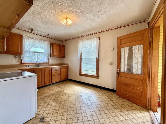 15825 State Route 207, Mount Sterling, OH 43143 - kitchen with electric stove, a textured ceiling, light floors, and brown cabinets