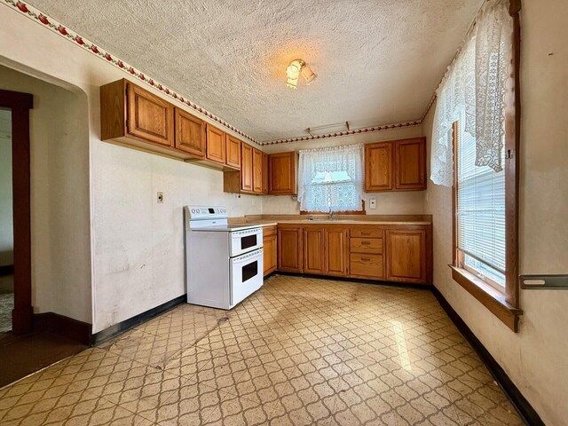 15825 State Route 207, Mount Sterling, OH 43143 - kitchen with double oven range, light flooring, a textured ceiling, brown cabinetry, and light countertops