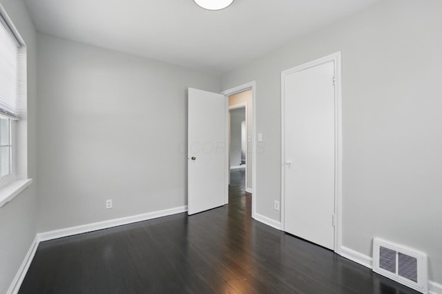 unfurnished bedroom featuring baseboards, visible vents, and dark wood-type flooring