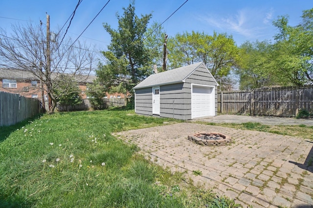view of yard with a fire pit, an outbuilding, a fenced backyard, and a garage