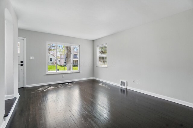 unfurnished living room featuring dark wood finished floors, baseboards, and visible vents