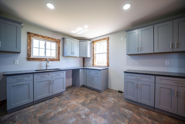 kitchen with recessed lighting, a sink, stone finish flooring, and a healthy amount of sunlight