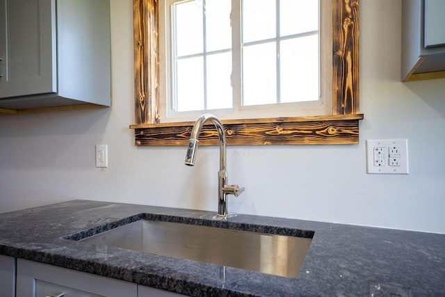 room details with a sink, gray cabinetry, and dark stone countertops