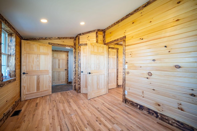 unfurnished room with wooden walls, recessed lighting, visible vents, and light wood-style floors
