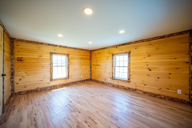 empty room featuring wooden walls, plenty of natural light, and wood finished floors