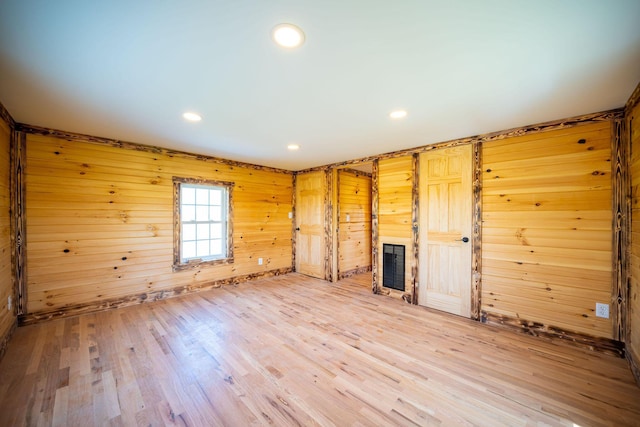 unfurnished living room featuring wooden walls, a fireplace, recessed lighting, and wood finished floors
