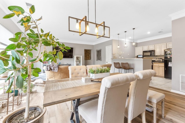 dining space with crown molding, recessed lighting, and light wood finished floors