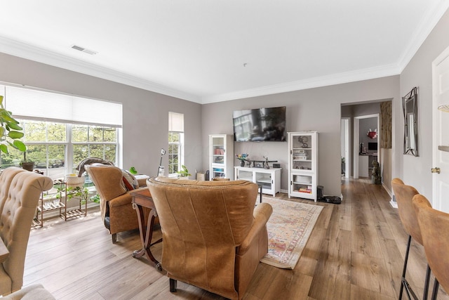 living room featuring visible vents, ornamental molding, and light wood-style floors