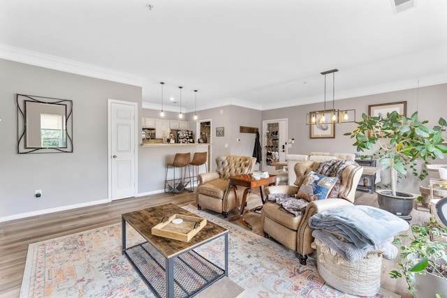 living room with visible vents, crown molding, wood finished floors, baseboards, and an inviting chandelier