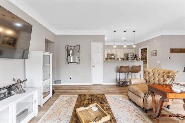 living area featuring crown molding, baseboards, and light wood finished floors