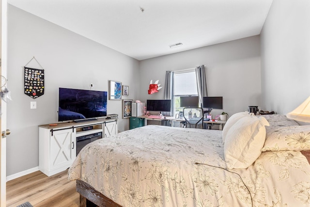 bedroom with light wood-style floors, baseboards, and visible vents