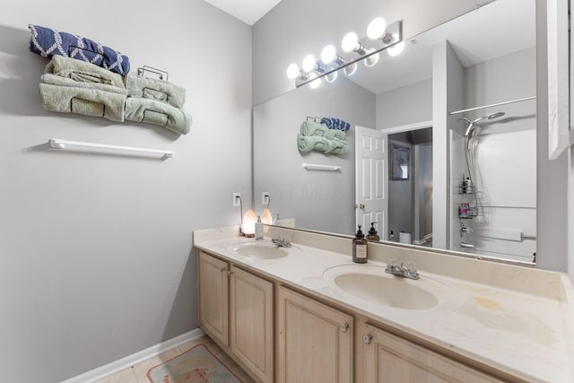 bathroom with double vanity, walk in shower, a sink, and tile patterned flooring