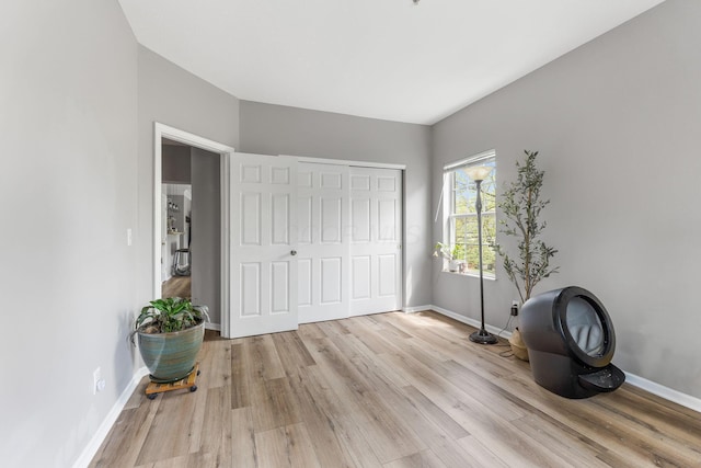 unfurnished bedroom with baseboards, light wood-style flooring, and a closet