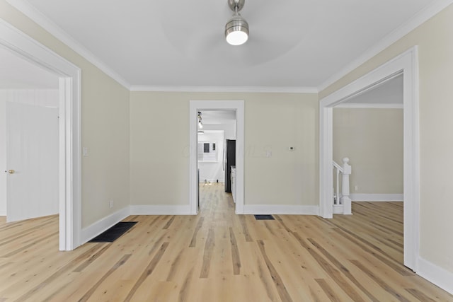 unfurnished room featuring light wood-style floors, visible vents, crown molding, and baseboards