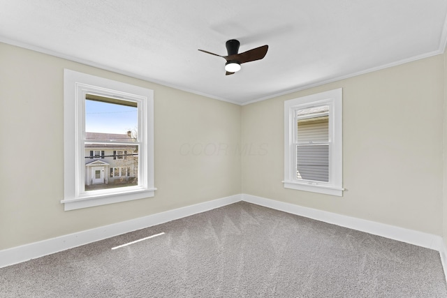 empty room featuring crown molding, carpet floors, a ceiling fan, and baseboards