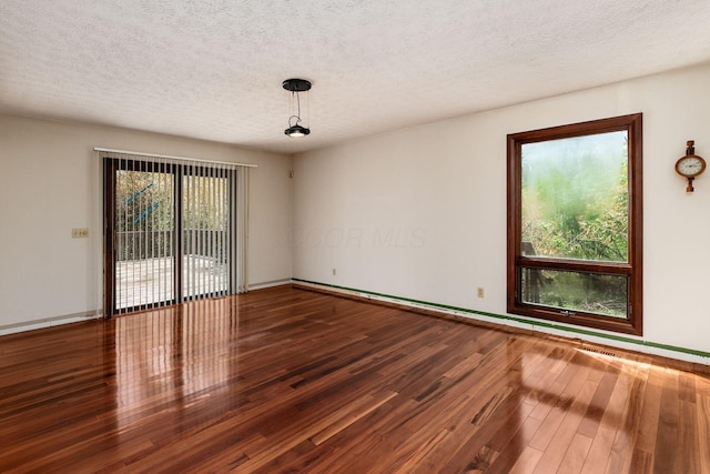 unfurnished room featuring baseboards, wood finished floors, and a textured ceiling