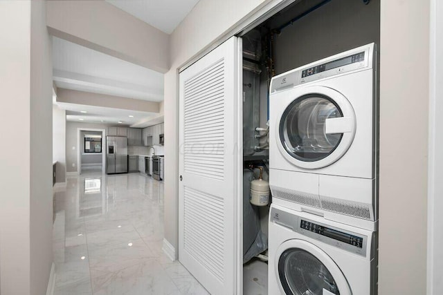 50 W Broad St Unit 2104, Columbus, OH 43215 - laundry room with baseboards, marble finish floor, stacked washing maching and dryer, and laundry area
