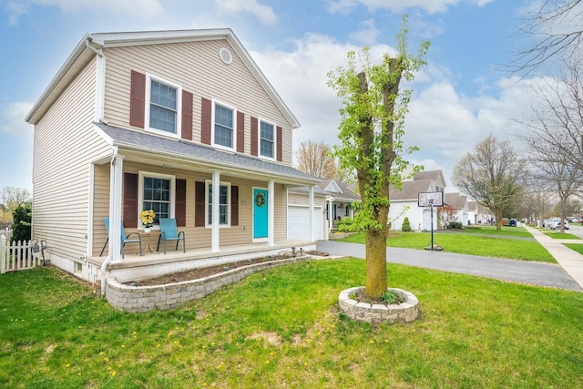 traditional home featuring fence, a front yard, covered porch, and aphalt driveway