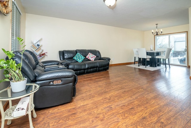 living room with baseboards, a notable chandelier, and wood finished floors