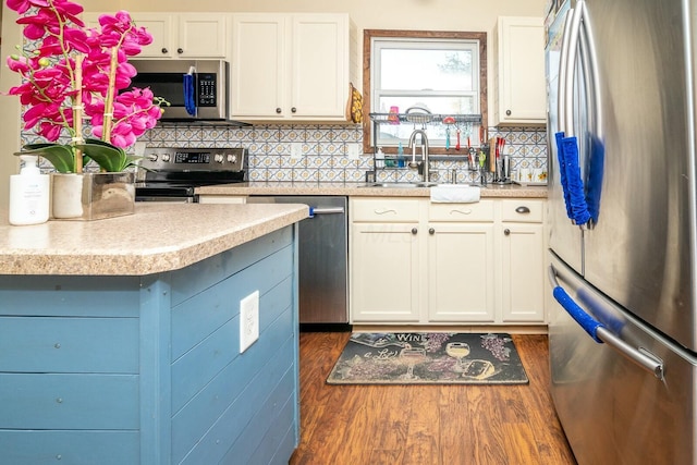 kitchen featuring a sink, white cabinets, stainless steel appliances, light countertops, and dark wood finished floors