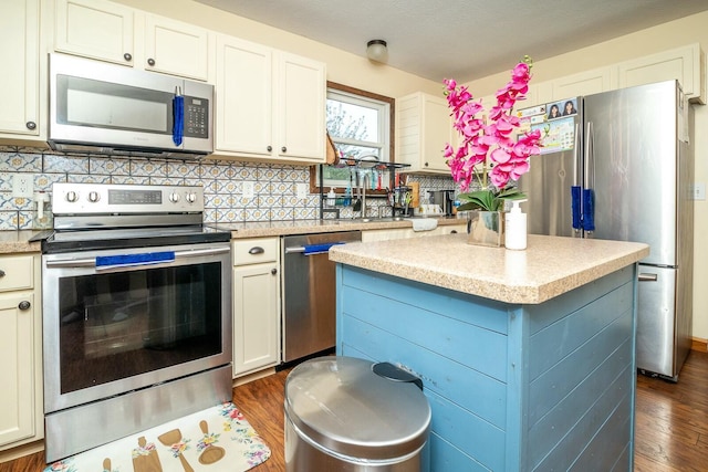 kitchen with stainless steel appliances, dark wood finished floors, decorative backsplash, light countertops, and a kitchen island