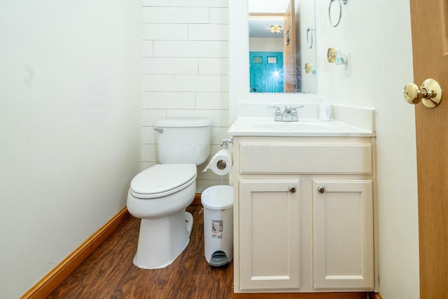 half bath with wood finished floors, toilet, and vanity