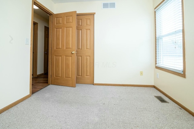 carpeted empty room featuring baseboards and visible vents