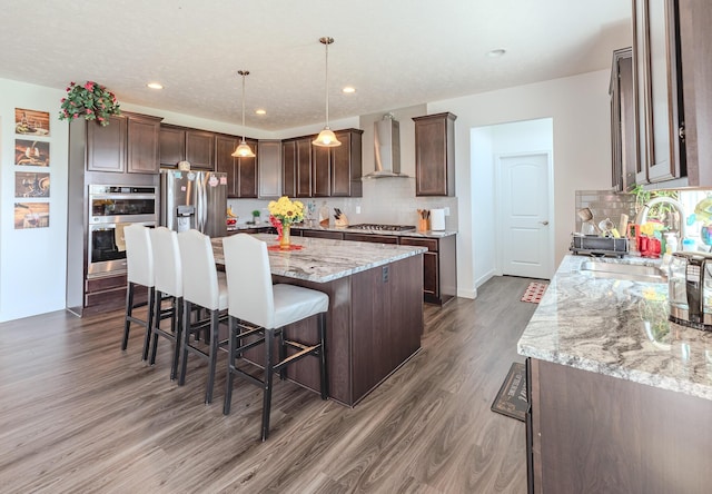 9295 Dewitt Dr, Plain City, OH 43064 - kitchen with dark brown cabinetry, a sink, wall chimney exhaust hood, stainless steel appliances, and dark wood-style floors