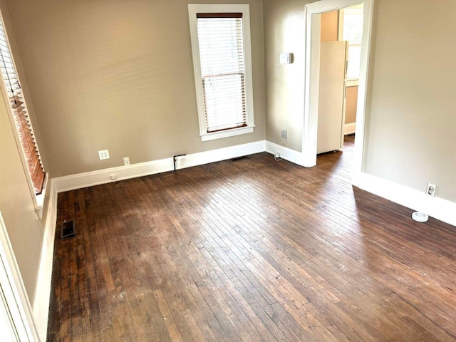 unfurnished room featuring baseboards, hardwood / wood-style flooring, visible vents, and a healthy amount of sunlight