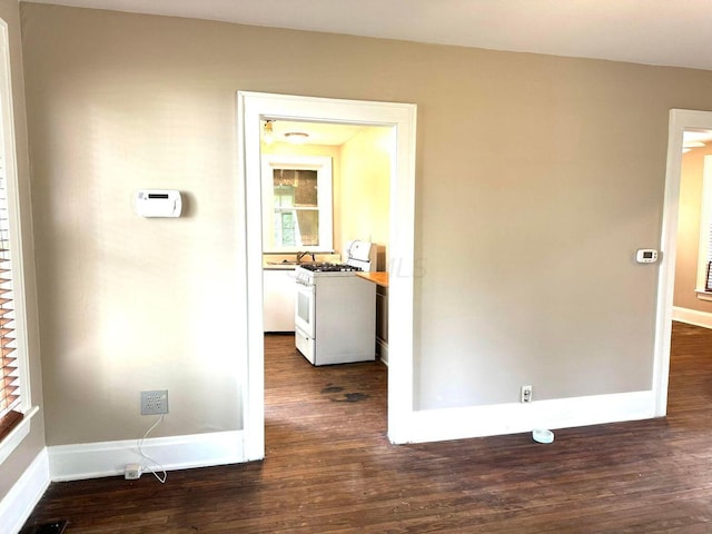 hallway featuring dark wood-type flooring and baseboards