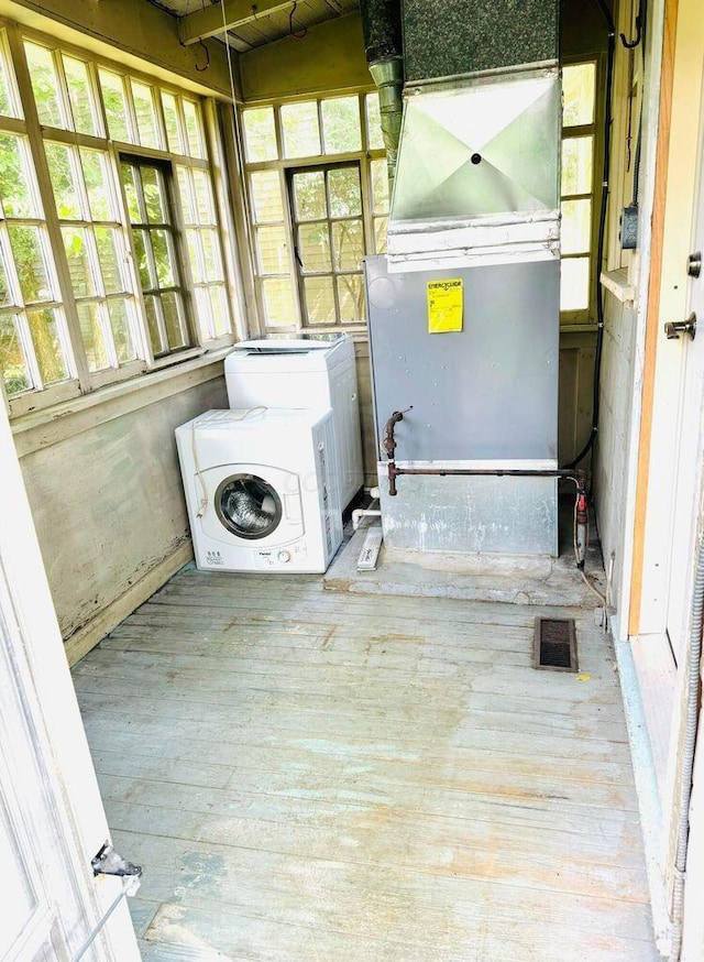 laundry area featuring heating unit, hardwood / wood-style flooring, laundry area, and washer / dryer