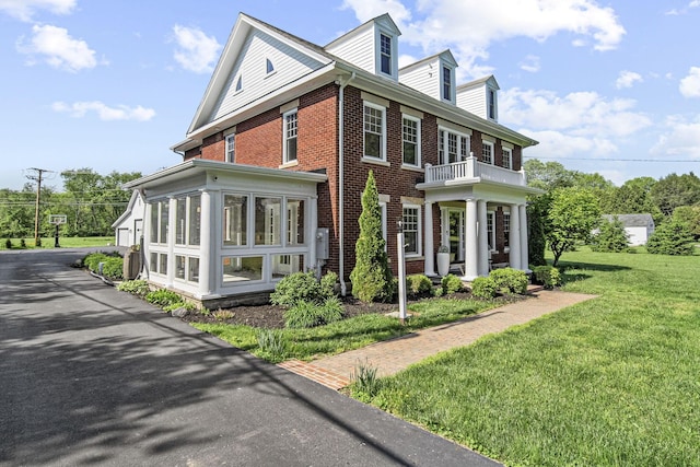 1812 Newark Granville Rd, Granville, OH 43023 - view of home's exterior with brick siding, a balcony, a lawn, and a sunroom