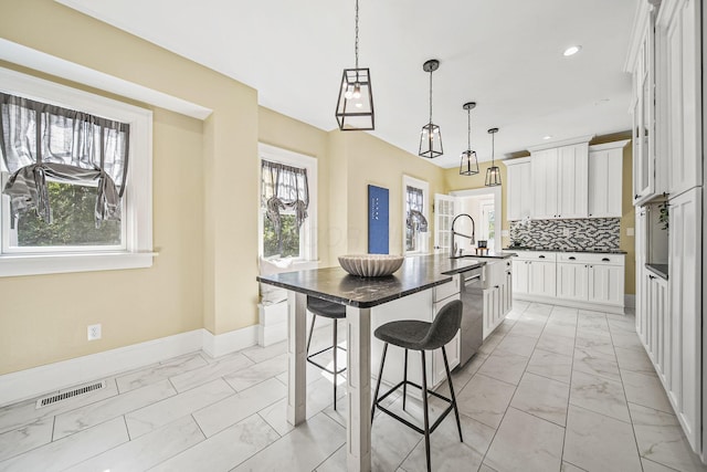 1812 Newark Granville Rd, Granville, OH 43023 - kitchen featuring light marble finish flooring, stainless steel dishwasher, a kitchen breakfast bar, baseboards, and a large island