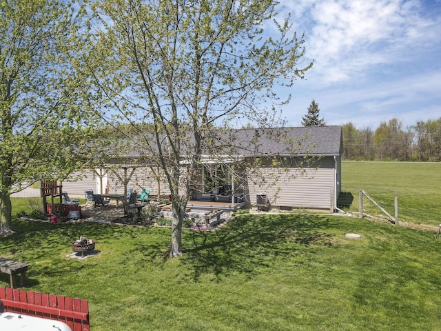 rear view of house featuring a lawn, a fire pit, and roof with shingles