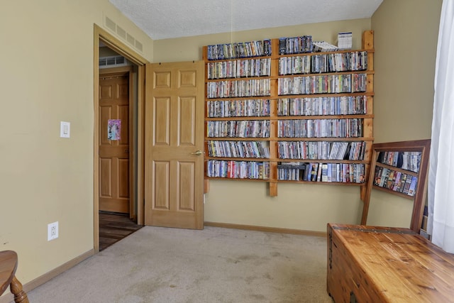 sitting room with carpet floors, a textured ceiling, baseboards, and visible vents