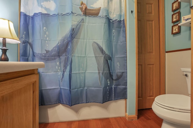 full bathroom featuring wood finished floors, toilet, and curtained shower