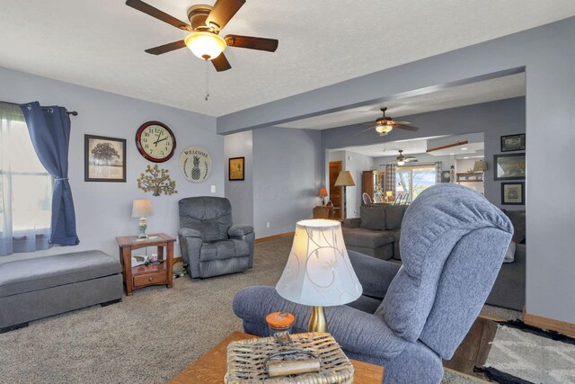living area with baseboards, a ceiling fan, and carpet flooring