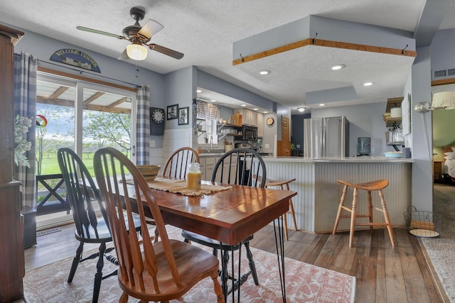 dining space with a textured ceiling, ceiling fan, and hardwood / wood-style flooring