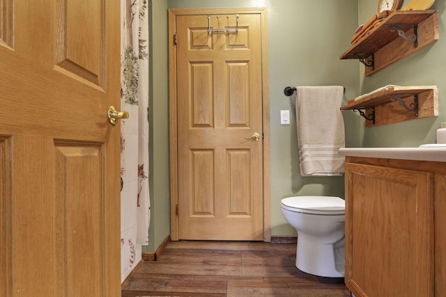 bathroom with vanity, baseboards, toilet, and wood finished floors