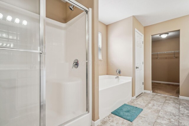 2128 Clay Stone Pl, Reynoldsburg, OH 43068 - bathroom with a spacious closet, a garden tub, a shower stall, and baseboards