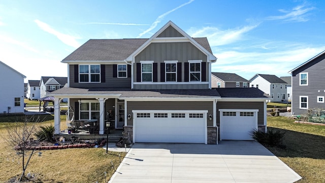 view of front facade with stone siding, board and batten siding, driveway, a porch, and a front yard