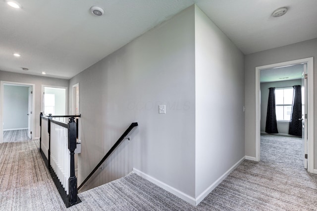 hall with baseboards, an upstairs landing, carpet floors, and recessed lighting