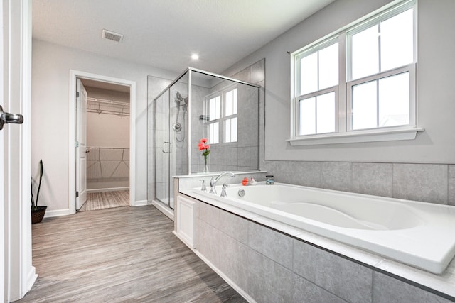 full bath featuring a walk in closet, wood finished floors, visible vents, and a stall shower