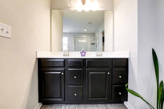 full bath featuring double vanity, a shower stall, baseboards, and a sink