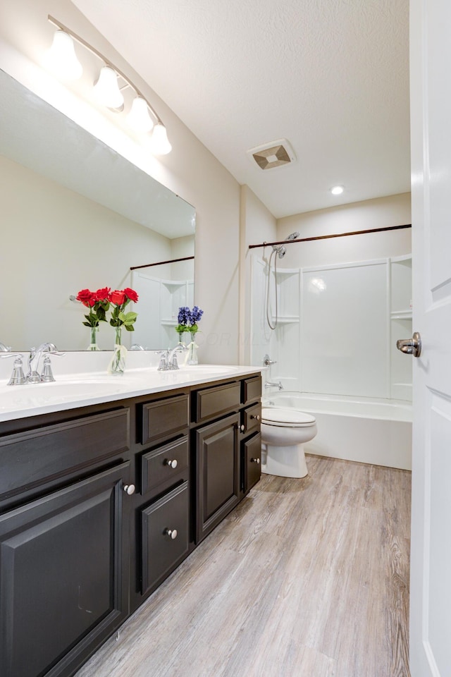 full bathroom with toilet, wood finished floors, a sink, and double vanity