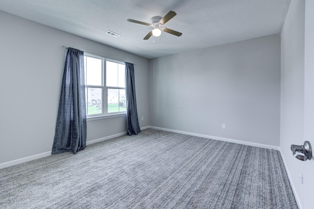 empty room featuring carpet, a ceiling fan, visible vents, and a textured ceiling