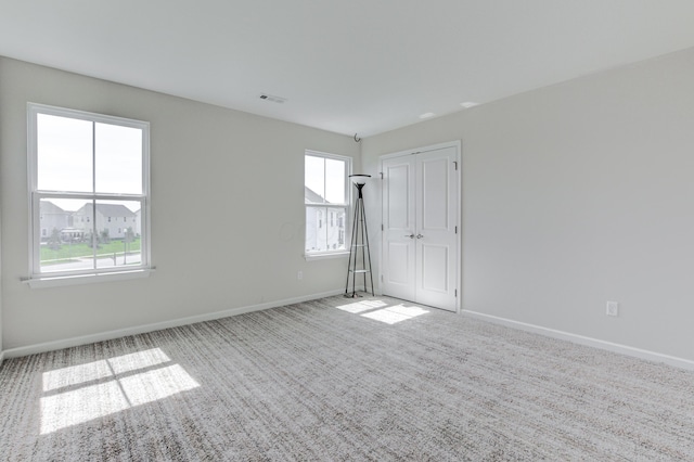 carpeted empty room featuring visible vents and baseboards