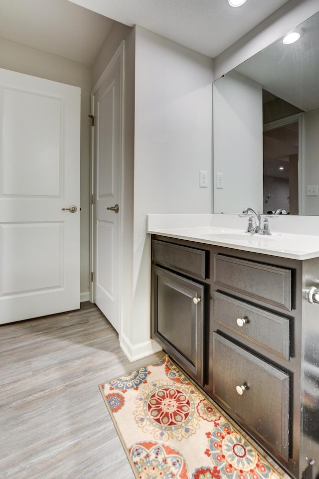 bathroom featuring baseboards, wood finished floors, and vanity