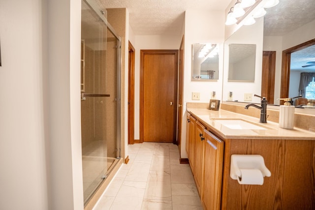 bathroom featuring a textured ceiling, vanity, and a stall shower