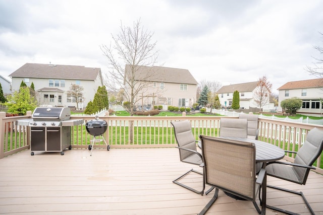 wooden deck featuring a residential view, outdoor dining space, a lawn, and a grill